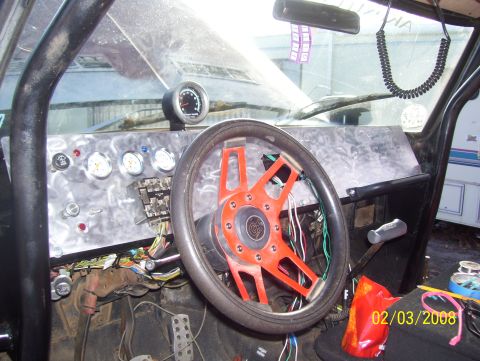 1978 Ford Bronco - The interior of a vehicle shows a custom dashboard with multiple gauges and an aftermarket steering wheel, with wiring visible.