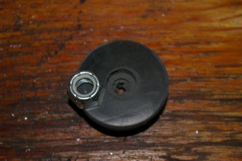 1986 Ford Bronco - A close-up view of a rubber bumper and a nylon lock nut resting on a wooden surface.
