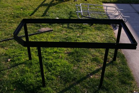 1986 Ford Bronco - A black metal rack frame sits on the grass, with another silver rack visible in the background.