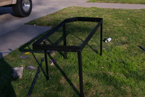 1986 Ford Bronco - A metal frame is assembled on a lawn, with a truck tire visible nearby.