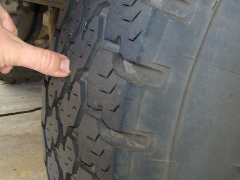 1989 Ford Bronco - Close-up of a tire tread pattern with a finger indicating a specific section.