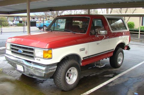 1989 Ford Bronco - This two-tone Ford Bronco is parked under a covered area, showing its front-left side.