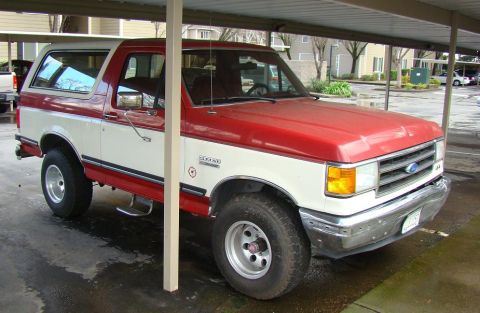 1989 Ford Bronco - This two-tone Ford Bronco is parked under a carport, showing its side and front quarter view.