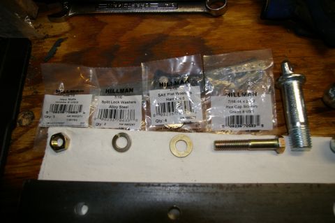 1986 Ford Bronco - Various hardware components including nuts, washers, and screws are laid out on a wooden surface.