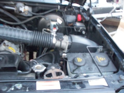 1996 Ford Bronco - Close-up view of a vehicle's engine bay components, including air intake and reservoirs.