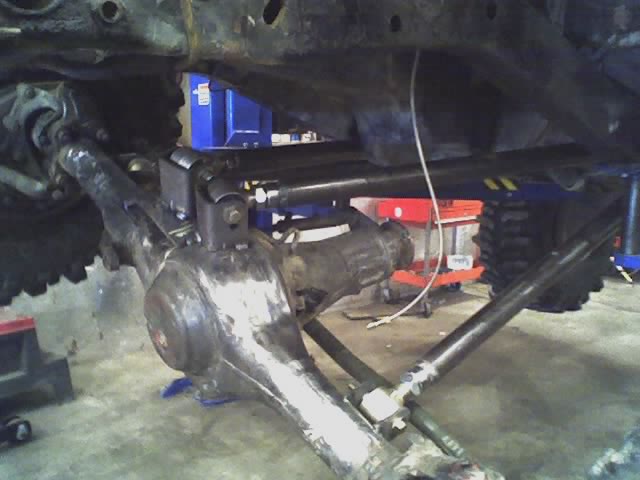 Undercarriage view showing suspension and differential components. A white wire hangs down