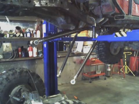 1992 Ford Bronco - A vehicle is being worked on in a garage, with its undercarriage elevated on a lift.