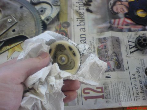 1986 Ford Bronco - A hand cleans a car part over a newspaper with various articles and images.