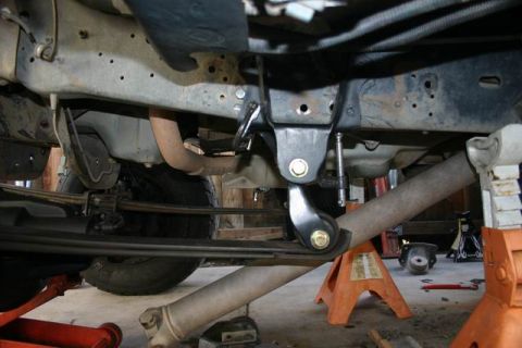 1991 Ford Bronco - The underside of a truck, showing its suspension system and exhaust pipe, is supported by orange jack stands.