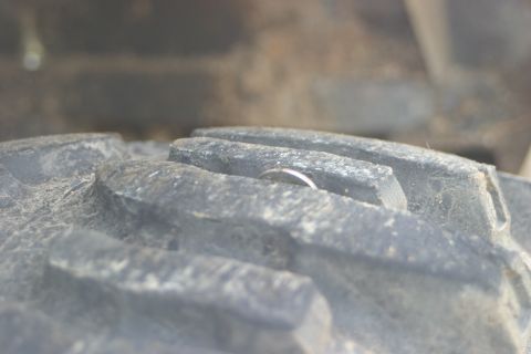 1995 Ford Bronco - A coin is lodged in the deep tread of a vehicle tire.