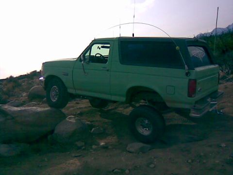 1996 Ford Bronco - A green Ford Bronco navigates a rocky off-road trail.
