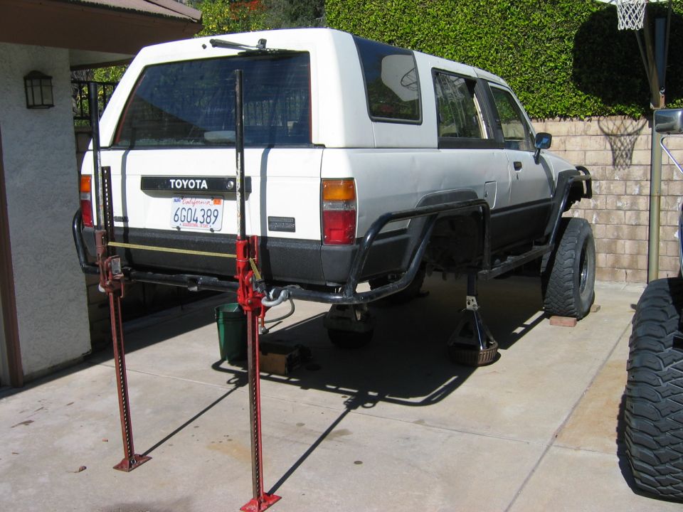 1985 Toyota 4Runner rear end raised on Hi-Lift jacks for maintenance, California license plate 6G04389 visible