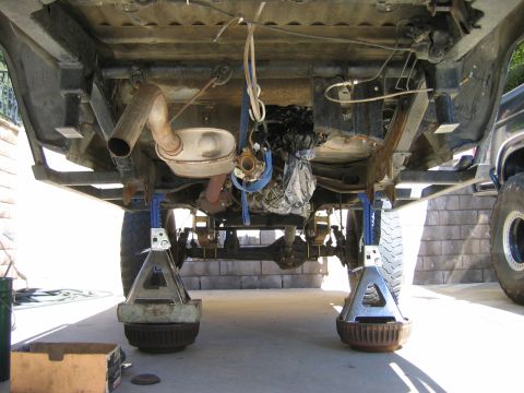 1985 Toyota 4Runner - The undercarriage of a vehicle is elevated on jack stands for maintenance, revealing its exhaust system and rear axle.