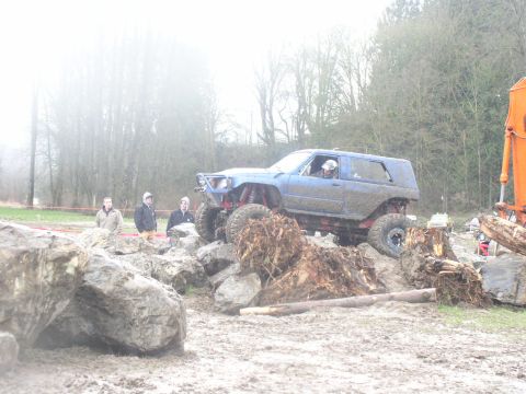 Blue off-road SUV with large tires climbing over rocks and debris