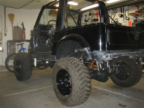 1987 Suzuki Samurai - This 1987 Suzuki Samurai is modified with large off-road tires and appears to be undergoing some work in a garage.