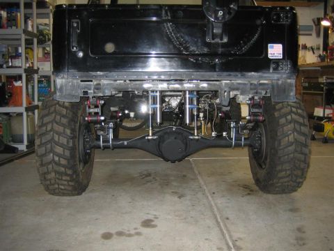 1987 Suzuki Samurai - Custom rear suspension and axle assembly on a vehicle, viewed from the back.