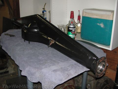 1968 Ford Mustang - A black metal part, possibly a driveshaft housing, rests on a table next to a can of brake cleaner and bottles.