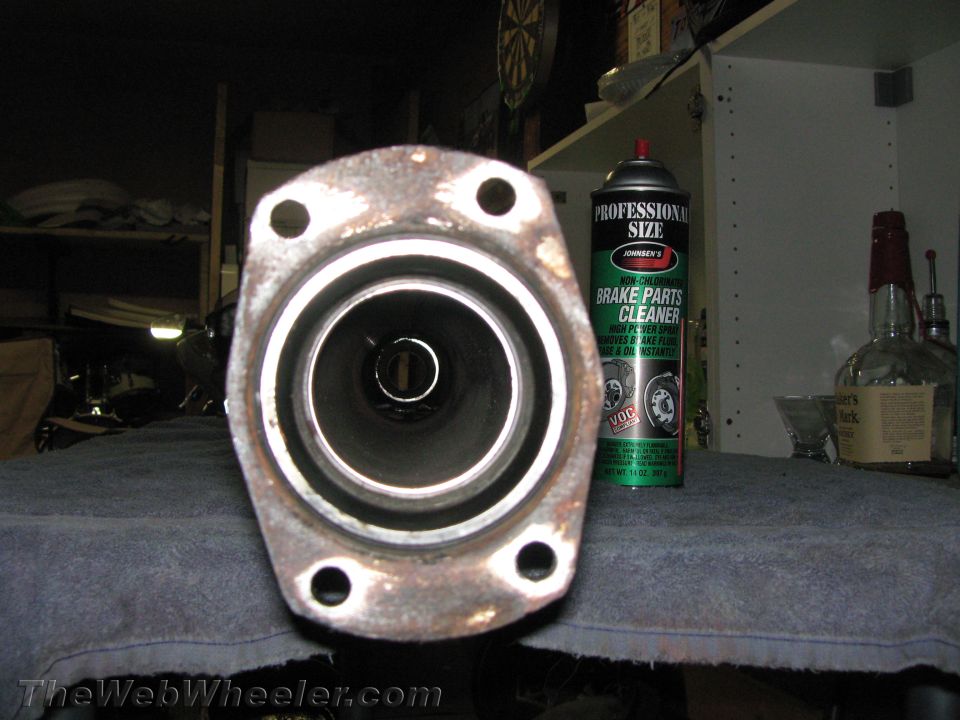 Exhaust pipe flange with four bolt holes, next to a can of brake parts cleaner