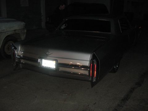 1968 Ford Mustang - Rear view of a silver 1971 Cadillac Coupe de Ville, its distinctive vertical taillights and chrome bumper.