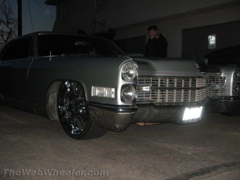1968 Ford Mustang - A silver Cadillac with custom chrome wheels and a distinctive grille is parked, with another vehicle visible behind it.