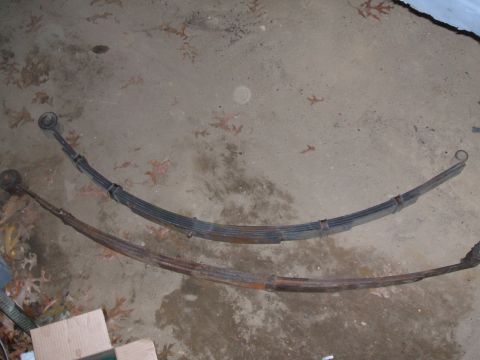 1969 Ford Torino - Two leaf springs, one in better condition than the other, are laid out on a concrete surface.