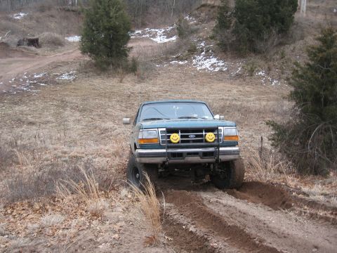 1996 Ford Bronco - 1996 Ford Bronco navigates an off-road trail in a wooded area during winter.