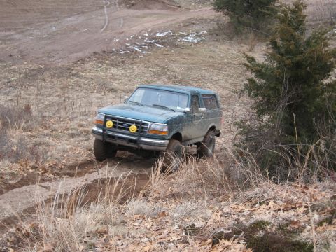 1996 Ford Bronco - This 1996 Ford Bronco navigates a challenging off-road terrain with muddy tracks.