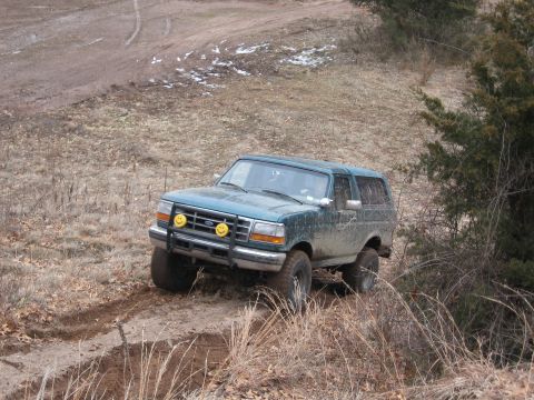 1996 Ford Bronco - A 1996 Ford Bronco navigates a muddy trail, kicking up dirt as it goes.