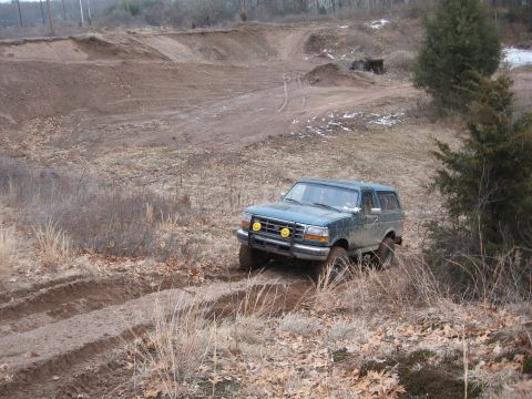 1996 Ford Bronco - A green Ford Bronco navigates a dirt track in an off-road area.