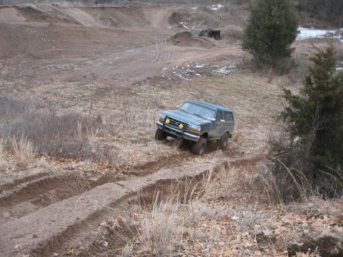 1996 Ford Bronco - 1996 Ford Bronco navigates a challenging off-road terrain with visible tire tracks.