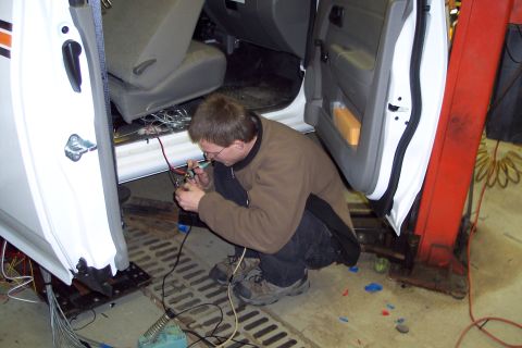 2001 Ford Crown Victoria - Technician works on the electrical wiring inside the door jamb of a vehicle.