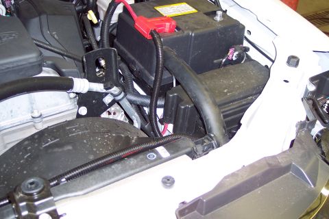 2001 Ford Crown Victoria - Close-up view of a vehicle's engine bay, focusing on the battery, various hoses, and the fan shroud.