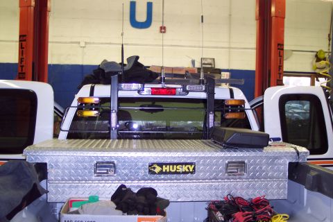 2001 Ford Crown Victoria - Diamond plate toolbox and headache rack installed on the bed of a white pickup truck, seen in a garage setting.