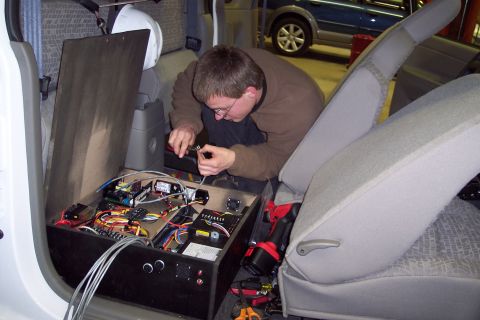 2001 Ford Crown Victoria - Man works on complex wiring and electronics installed in the interior of a vehicle.