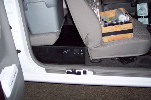 2001 Ford Crown Victoria - The interior of a vehicle shows a custom-installed black box with controls and a first aid kit mounted on the door.