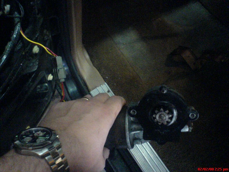 Hand holding a car starter motor with wires connected