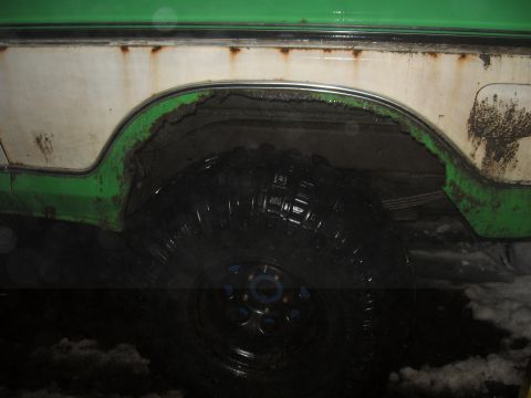 1979 Ford Bronco - Close-up of a vehicle's rear wheel well, showing rust and a large tire.