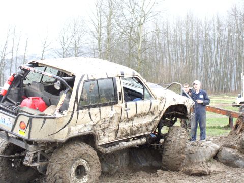 Mud-covered off-road SUV with large tires and a roll cage