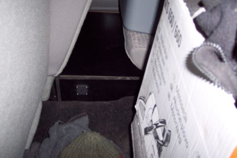 2001 Ford Crown Victoria - The interior cargo area shows a box and some clothing items, with a dark floor and grey upholstery.
