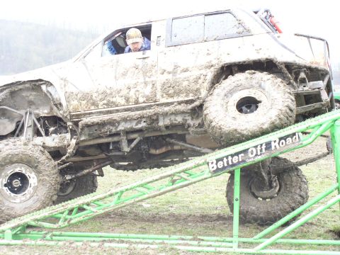 Mud-covered SUV with large tires on a green ramp