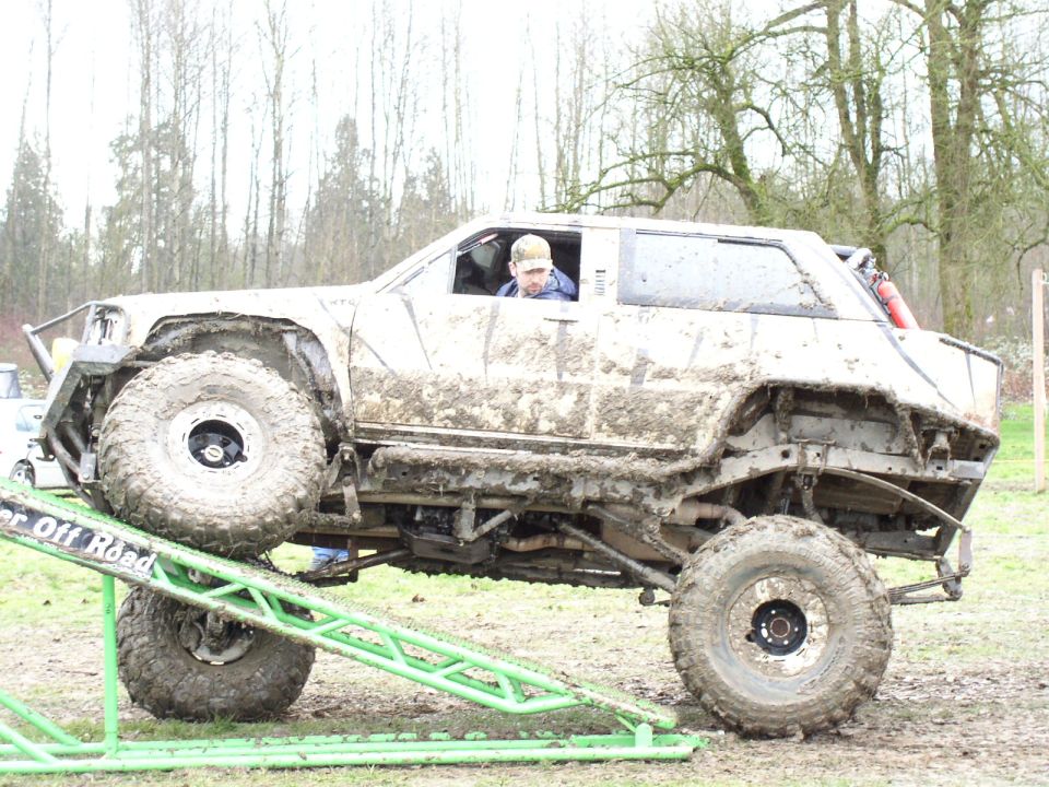 Mud-covered off-road vehicle on a ramp, side view