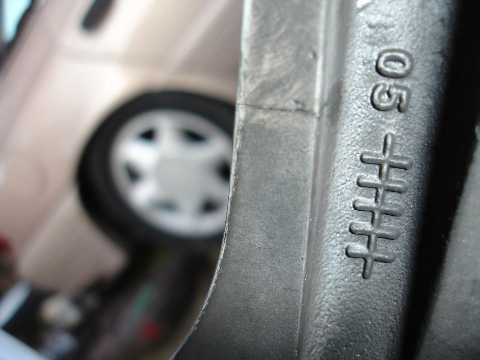 Close-up of a silver wheel rim with stamped markings '05' and '+++++' visible