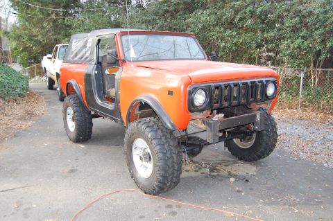 1994 Ford Bronco - International Harvester Scout II in orange, with a white pickup truck behind it.