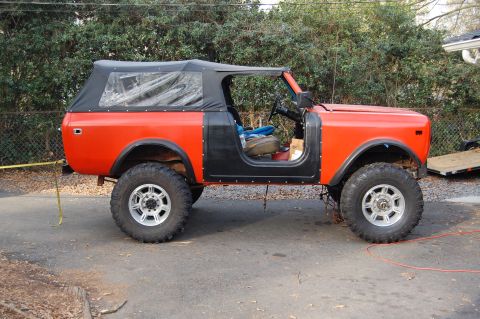 1994 Ford Bronco - An orange International Harvester Scout II with a black soft top and removed doors sits parked outdoors.