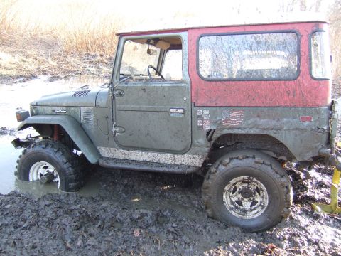 1976 Toyota Land Cruiser - This vintage Toyota Land Cruiser is partially submerged in thick mud, with its tires struggling for traction.