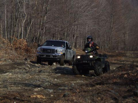 1976 Toyota Land Cruiser - A pickup truck and an ATV with two riders navigate a rocky, wooded path.