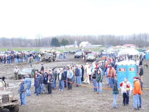 Muddy field with off-road vehicles and crowds gathered