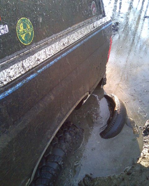 1989 Ford Bronco - Vehicle stuck in mud and water, with a spare tire submerged in the muck.