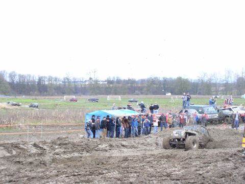 Off-road vehicles stuck in mud with spectators watching