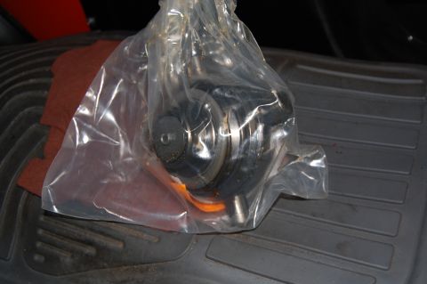 1994 Ford Bronco - A vehicle part is sealed in a plastic bag and rests on a textured floor mat.